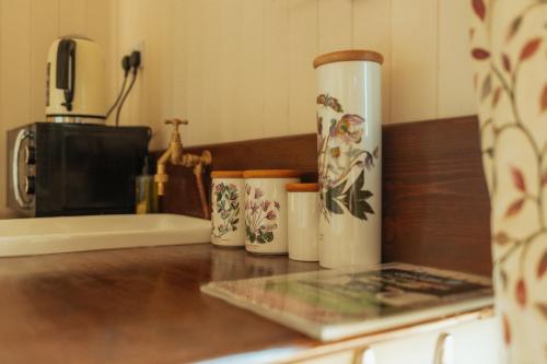a counter with four coffee cups on a counter top at Glamping in Wiltshire in our luxury Shepherds Hut in Chippenham