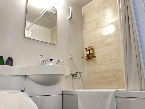 a white bathroom with a shower and a sink at Global Resort ONO de LUNE in Hatsukaichi