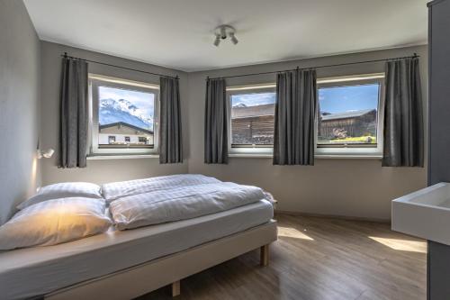 a bedroom with a bed with two windows and a sink at Haus am Bach in Kaprun