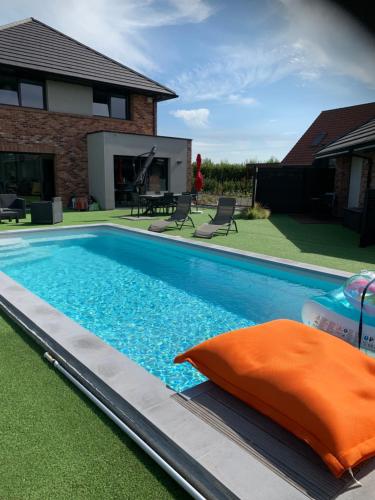Lorgies的住宿－Les Chambres de Lily 2，一座游泳池,旁边是一座房子,上面有橙色枕头