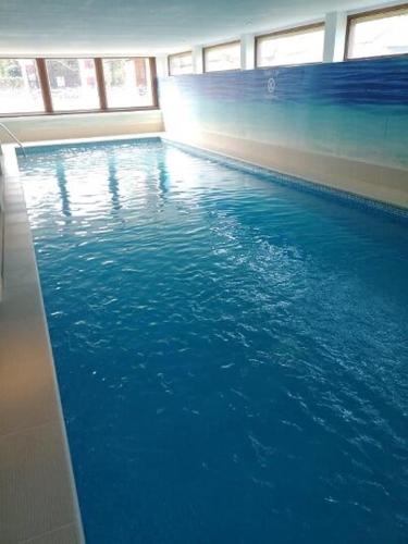 une piscine avec de l'eau bleue dans un immeuble dans l'établissement La Petite Maison, à Désertines
