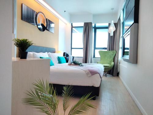 a hotel room with a bed and a green chair at CentreStage PJ by HomeBrickz in Petaling Jaya