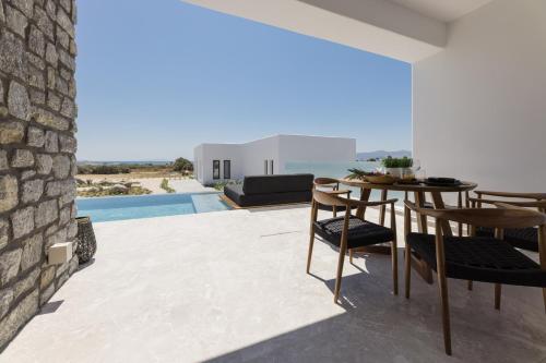 a patio with a table and chairs and a pool at Milestones Naxos in Naxos Chora