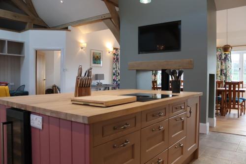 a kitchen with an island with a tv on the wall at The Anchorage Nables Farm in Chippenham
