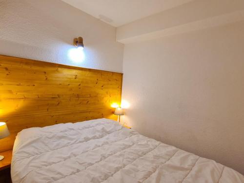 - une chambre avec un lit blanc et un mur en bois dans l'établissement Studio cosy à Flaine avec terrasse et accès rapide aux pistes - FR-1-425-181, à Flaine