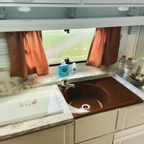 a sink in a kitchen with a window above it at Cosy Caravan at Carrigeen Glamping in Kilkenny