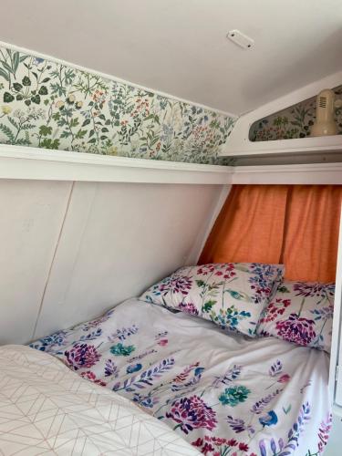 Cama en habitación pequeña con papel pintado con motivos florales en Cosy Caravan at Carrigeen Glamping en Kilkenny