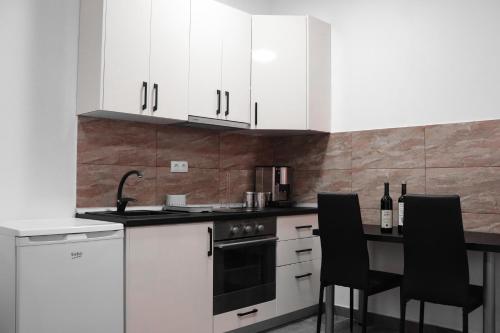 a kitchen with white cabinets and a table with black chairs at Stan na dan Sebastijan in Banja Luka