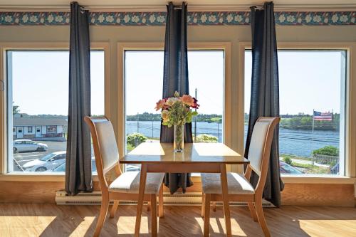 a dining room table with chairs and a vase of flowers at Novastar Motel On The Lake in Yarmouth