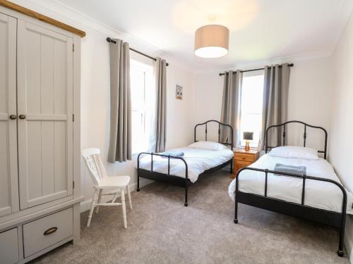 a bedroom with two beds and a chair and windows at The House in Gorleston in Great Yarmouth