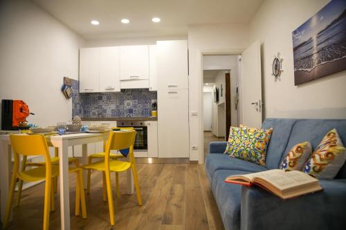 sala de estar con sofá azul, mesa y sillas en Filoblu appartamento Formia, en Formia