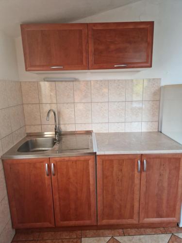 une cuisine avec des armoires en bois et un évier dans l'établissement Apartments Rora, à Rogoznica