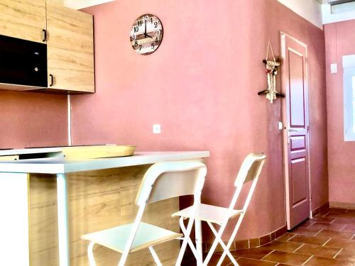 a kitchen with two white chairs and a table at Domaine Plan des Devens in Roussillon