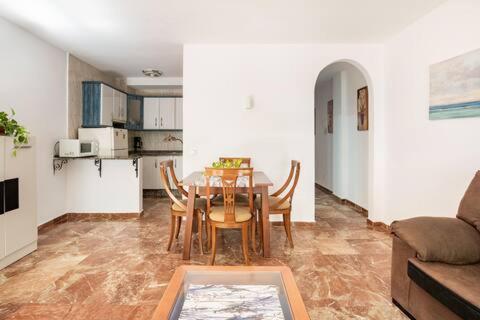a dining room with a table and chairs and a kitchen at Apartamento Playa Maria con parking in Fuengirola