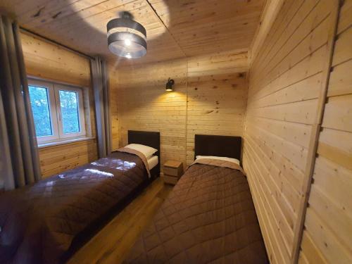 a bedroom with two beds in a room with wooden walls at Bukowa Ostoja in Nakielno