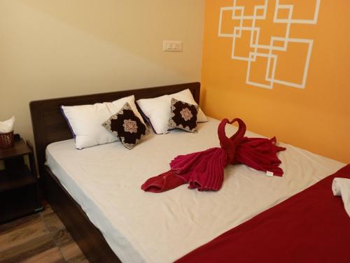 a bed with red sheets and pillows on it at Arangan Kudil in Tiruchirappalli