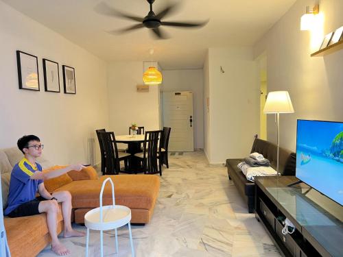 a man sitting on a couch playing a video game at BayView Suites Port Dickson By MAISON in Port Dickson