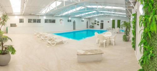 a pool with tables and chairs in a building at Hamburgo Palace Hotel in Balneário Camboriú