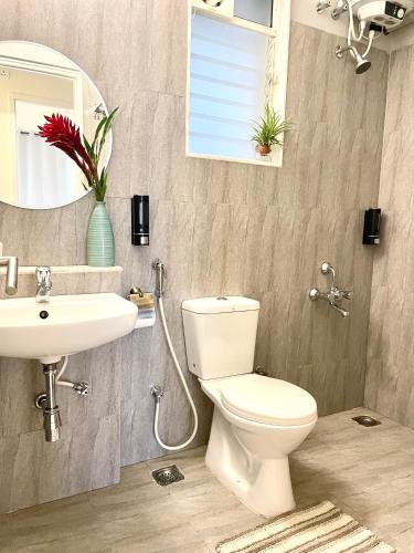 a bathroom with a toilet and a sink and a mirror at Platinum - Sun-kissed Holidays Goa in Dabolim