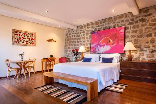 a bedroom with a large bed and a table at Barra do Piuva Porto Hotel in Ilhabela