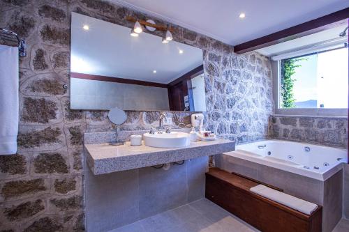 a bathroom with a sink and a tub and a mirror at Barra do Piuva Porto Hotel in Ilhabela