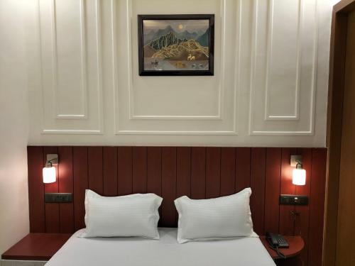a bed with two white pillows and a picture above it at Anushangi Hotel in Hisār