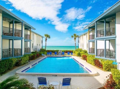 a pool in the courtyard of a building with a view of the ocean at Sunset Connection - Gulf Place in Holmes Beach