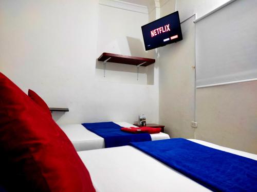 2 camas en una habitación con TV en la pared en Trip Monkey Hostel en San Gil