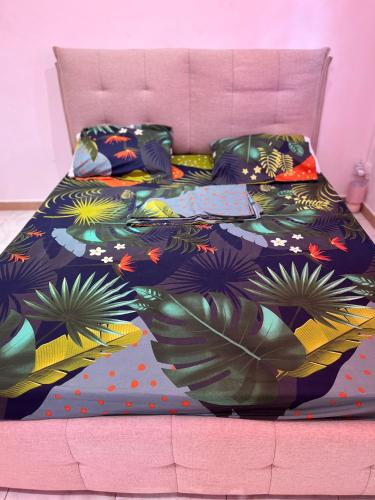 een bed met een kleurrijk dekbed met planten erop bij La petite Girafe in Baie-Mahault