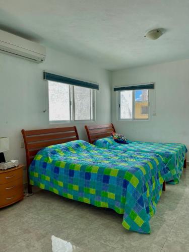 a bedroom with a bed with a blue and yellow blanket at Casa Familiar para hospedaje privado en Mérida in Mérida
