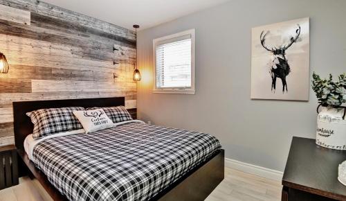 1 dormitorio con 1 cama y pared de madera en Condo 88 Chemin des Alpages by Les Chalets Alpins, en Stoneham