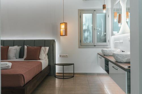a bedroom with a bed and a sink and a mirror at K suites ios in Ios Chora