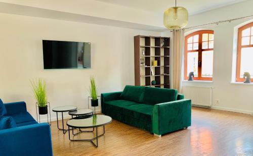a living room with a green couch and tables at Apartamenty Krasicki in Lidzbark Warmiński