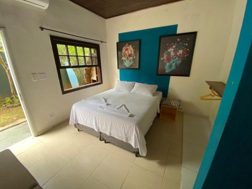 a bedroom with a white bed and a window at Tropical Casa Ubatuba in Ubatuba