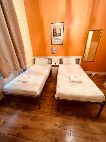 two twin beds in a room with orange walls at Gresham Hotel Bloomsbury in London
