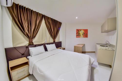 a bedroom with a white bed and a sink at Hotel Aracaju Suites in Aracaju