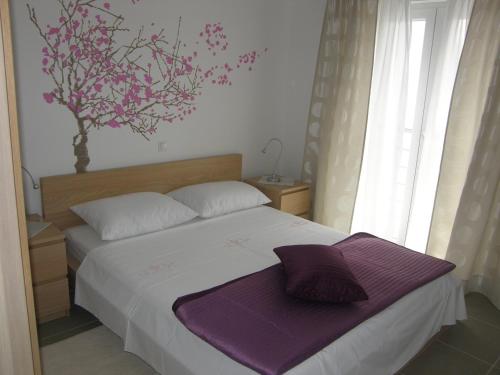 1 dormitorio con 1 cama con sábanas moradas y un árbol en la pared en Apartments Hrabric, en Baška