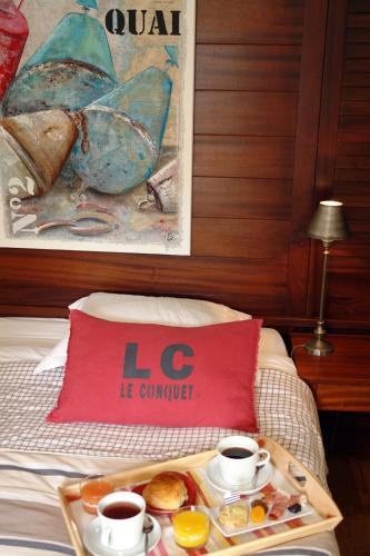 a tray of food on a bed with two cups of coffee at La Vinotière Chambres Appartements Spa in Le Conquet