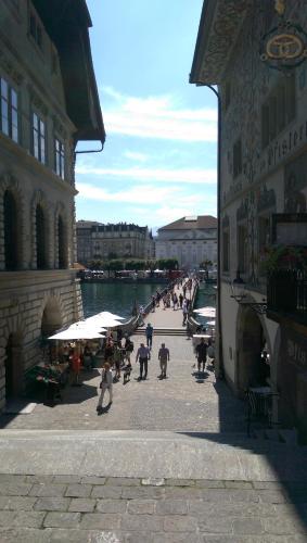 a group of people walking down a street next to a river at HITrental Zur Metzgern Apartments in Luzern