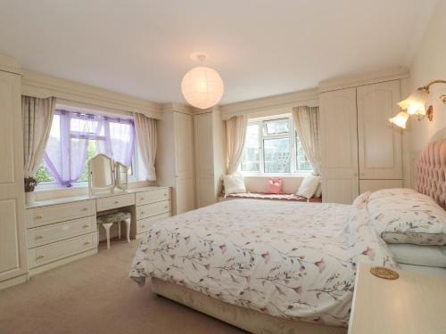 a bedroom with a bed and a desk and windows at Rhode Acres in Sturminster Newton