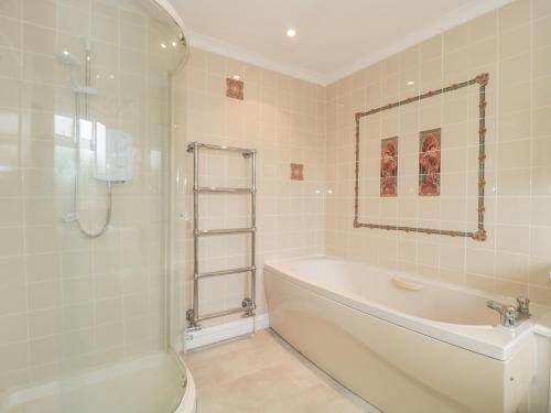 a bathroom with a tub and a shower and a sink at Rhode Acres in Sturminster Newton