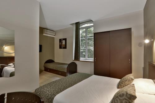 Una habitación de hotel con una cama y una ventana. en Le Coligny, en Brantôme