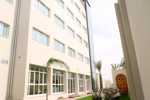 a large white building with tables and chairs in front of it at Hotel Delphin-Nouadhibou in Nouadhibou