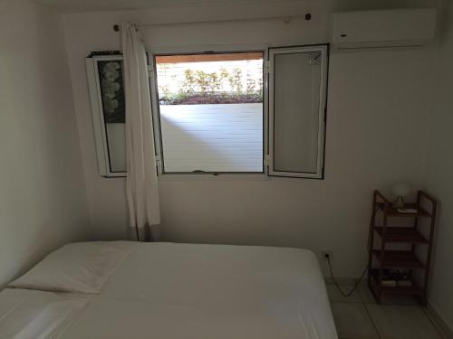 a bedroom with a white bed and a window at Bungalow Milo in Bouillante