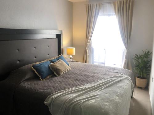 Un dormitorio con una cama con almohadas azules y una ventana en Gualdras Departments with parking 7min to downtown, en Guanajuato