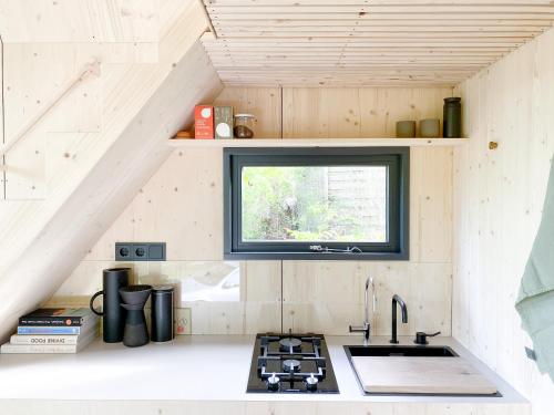 una pequeña cocina con fregadero y ventana en tinyzeit Urlaub im tiny house an der Flensburger Förde en Steinberg