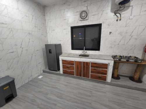 Zimmer mit einem TV und einer Theke mit einem Waschbecken in der Unterkunft Alshafaq chalet in Al ‘Aqar