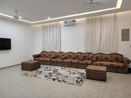 ein Wohnzimmer mit einem Sofa und einem TV in der Unterkunft Alshafaq chalet in Al ‘Aqar