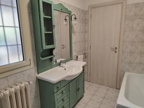 a green bathroom with a sink and a mirror at Alloggio Turistico C'era una volta in Roccalvecce