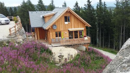 Cabaña de madera pequeña con porche y flores en Chalet Die Berghexn, en Klippitztorl